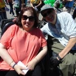 Two people in wheelchairs smile for a photo.