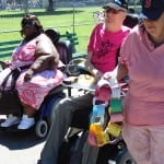 People in pink clothing, two people in wheelchairs holding paper chain.