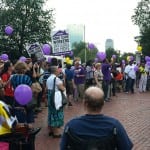A view of the crowd outside the State House. Many hold either yellow or purple balloons. Signs read "HOME CARE WORKERS INVISIBLE NO MORE"