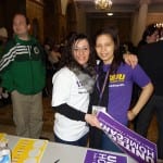 Two people take a picture wearing 1199SEIU t-shirts. One holds a United Home Care sign in their hand.