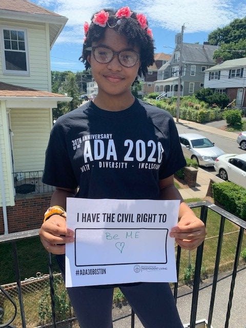 A person wearing a black ADA 30 t-shirt holds a sign that reads I HAVE THE CIVIL RIGHT TO BE ME.