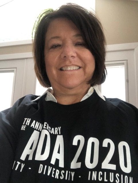 A person wearing a black ADA 30 t-shirt smiles for a photo.