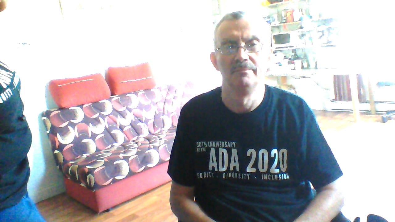 A person wearing a black ADA 30 t-shirt takes a photo.