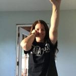A person wearing a black ADA 30 t-shirt smiles for a photo holding their fist in the air.